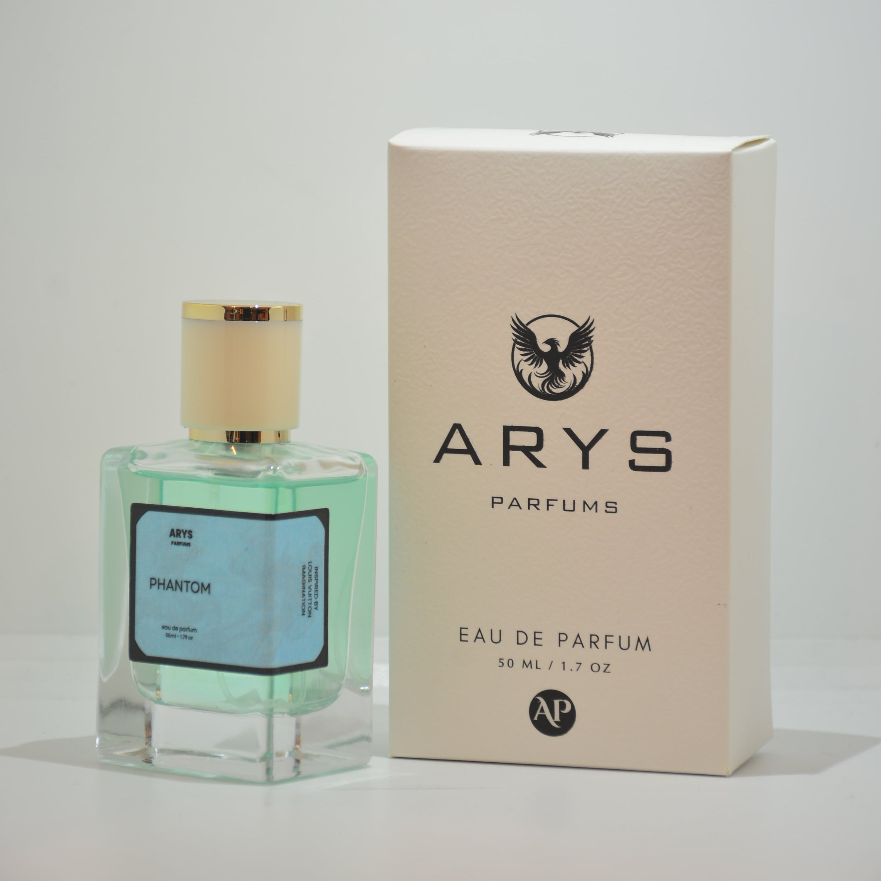 A bottle of Arys Parfums. with a light green liquid and gold cap, shown next to its beige packaging box on a white background. It is Phantom, inspired from Imagination by Louis Vuitton.